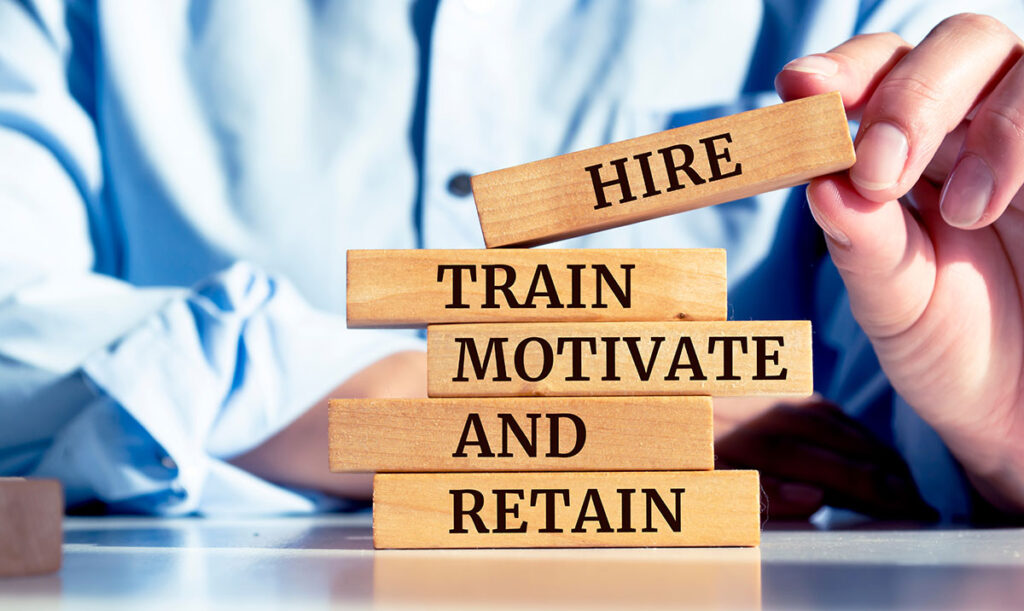 wooden blocks labeled "hire, train, motivate, and retain"